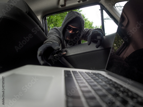 фотографія Crime concept - thief stealing laptop from the car. View from