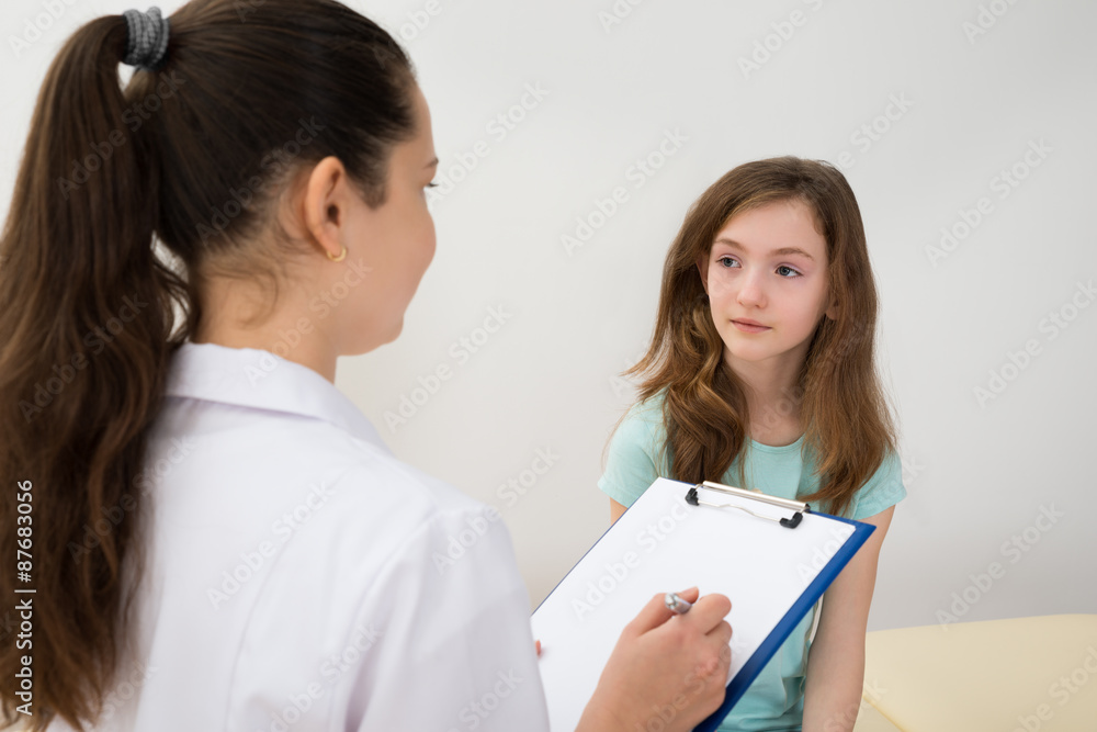 Doctor Writing On Clipboard In Front Of Patient Doctor Writing On Clipboard In Front Of Patient