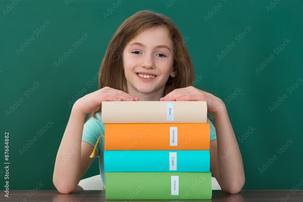 Girl Sitting At Desk With Stack Of Books Girl Sitting At Desk With Stack Of Books