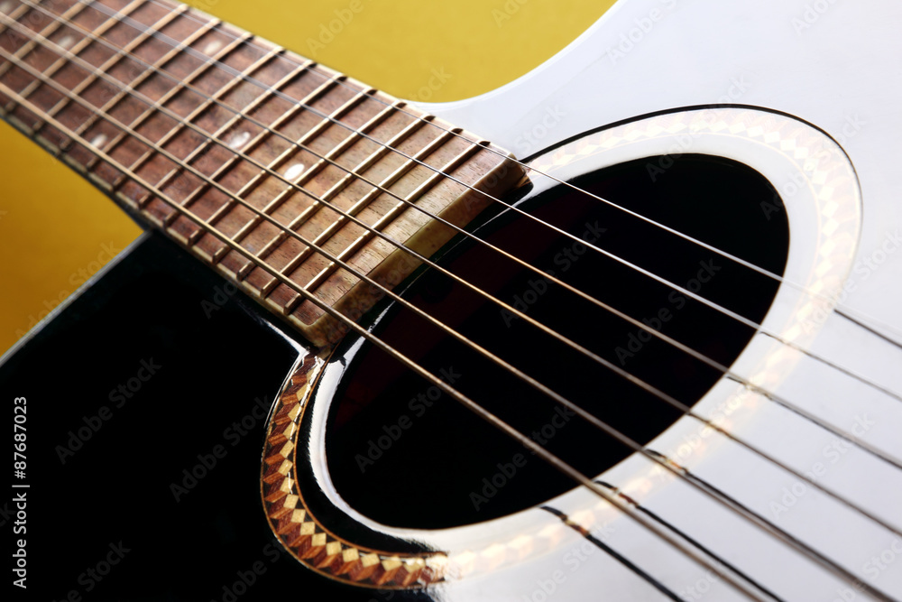 Detail of black acoustic guitar on yellow background Detail of black acoustic guitar on yellow background