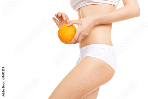 Beautiful female body with orange on a white background