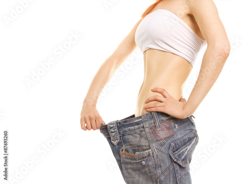 Photo of a young slim woman in oversized pair of old jeans.Isolated on white