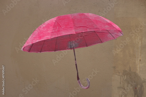 Foto parapluie rose.graffiti sur un mur.