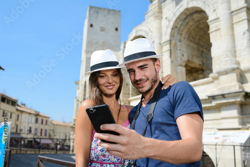 cheerful young couple of tourist visiting europe and making a selfie in front of a famous monument