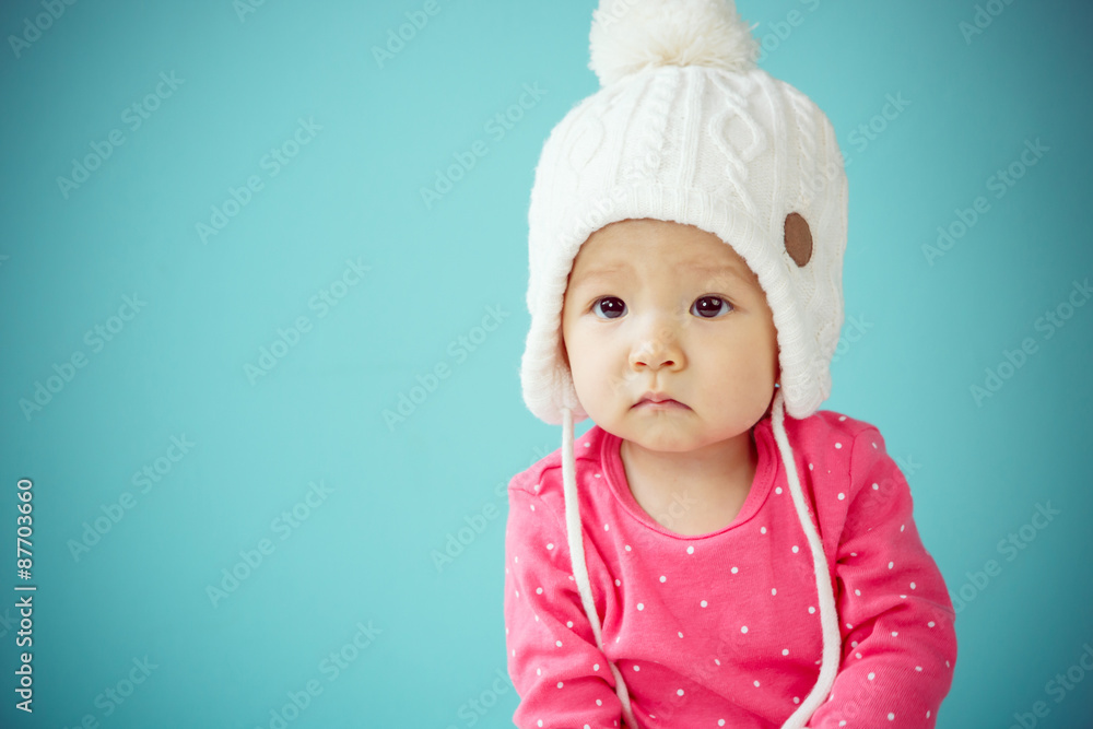 Little baby in knit winter clothing closing face with knitted be Little baby in knit winter clothing closing face with knitted be