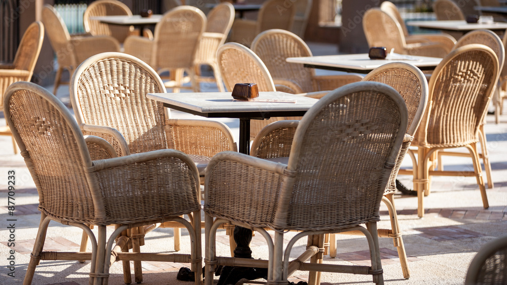 Al Fresco dining. A view across an outdoor restaurant with wicker chairs filling the view.