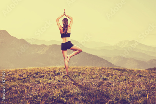 Woman practices yoga in the mountains photo