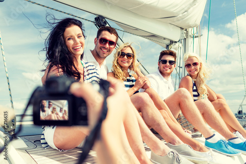 smiling friends photographing on yacht