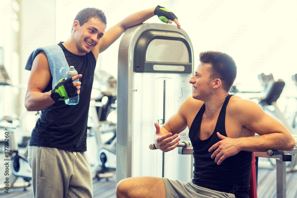 smiling men exercising on gym machine