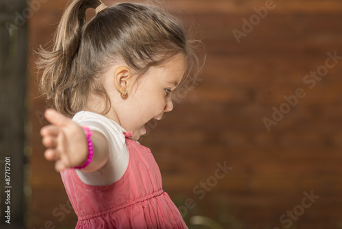 Outdoor portrait of expressive beautiful little girl smiling astonished