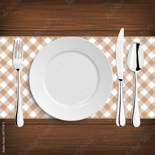 Plate with spoon, khife and fork on a wood table photo