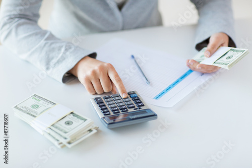 close up of hands counting money with calculator