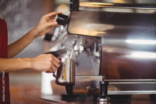 Barista steaming milk at the coffee machine