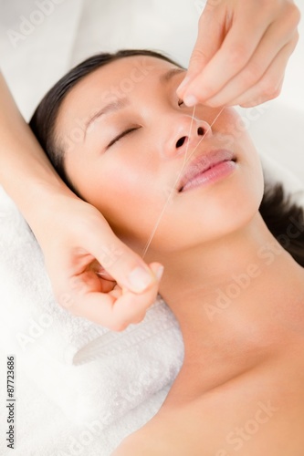 Hands threading beautiful womans face