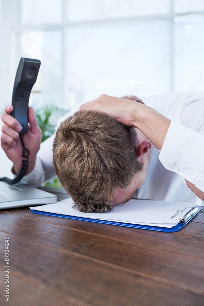 Naklejka premium Irritated businessman holding a land line phone