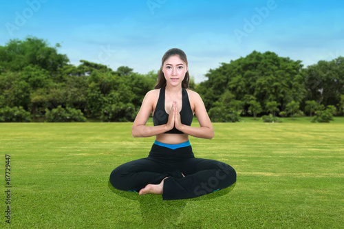 woman doing yoga exercise on grass with sky
