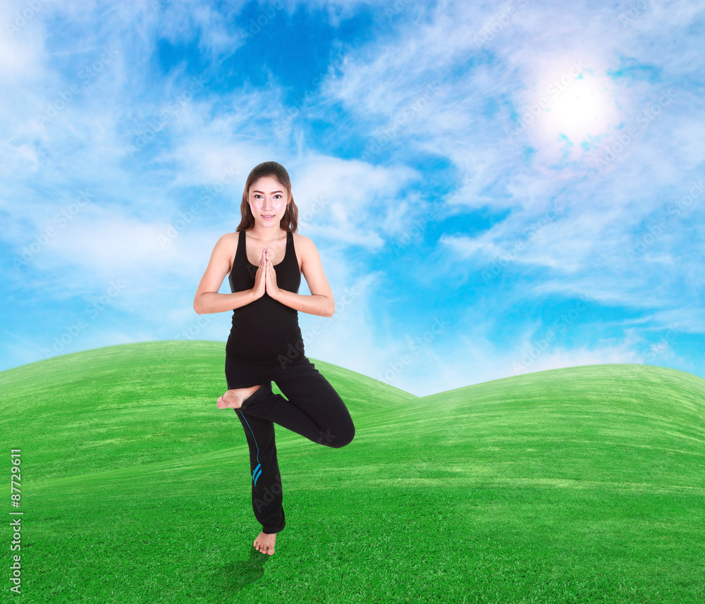 woman doing yoga exercise on grass with sky woman doing yoga exercise on grass with sky