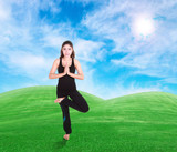 woman doing yoga exercise on grass with sky