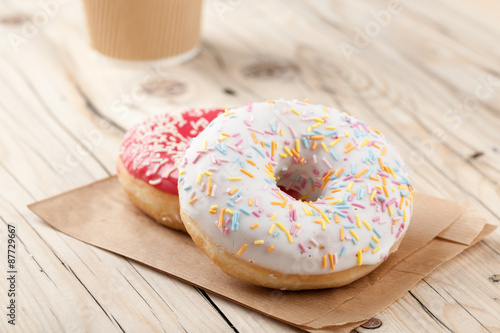 Colorful donuts and paper cup on wooden table