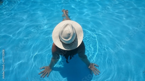 Bild auf Leinwand Mujer con sombrero relajada en la piscina