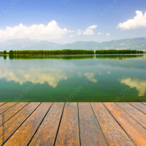 Empty wooden table for product presentation. In the background blurred lake and mountains
