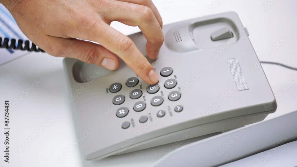 hands dialing number on desk set phone at office hands dialing number on desk set phone at office