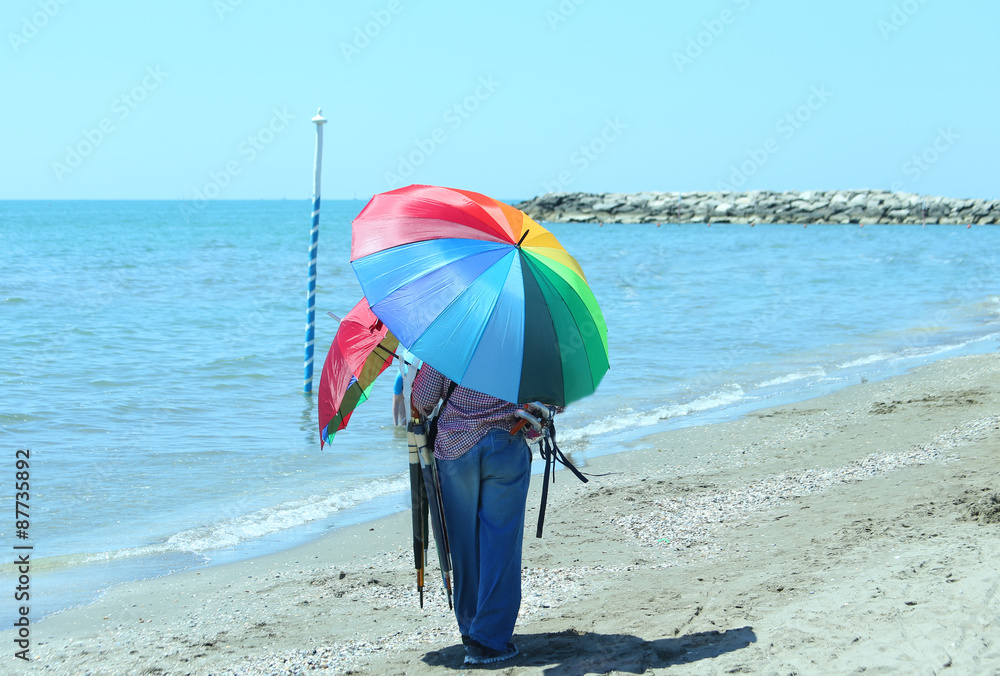 peddler of colorful umbrellas by the sea on the beach in summer