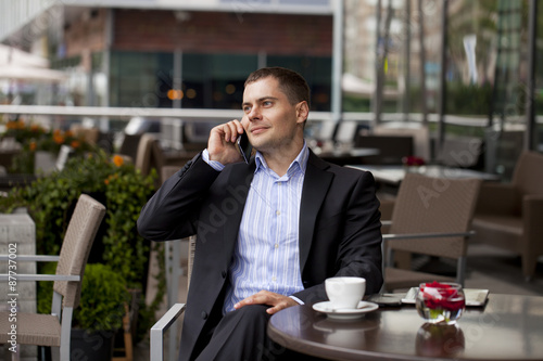 Cheerful young businessman calling by phone