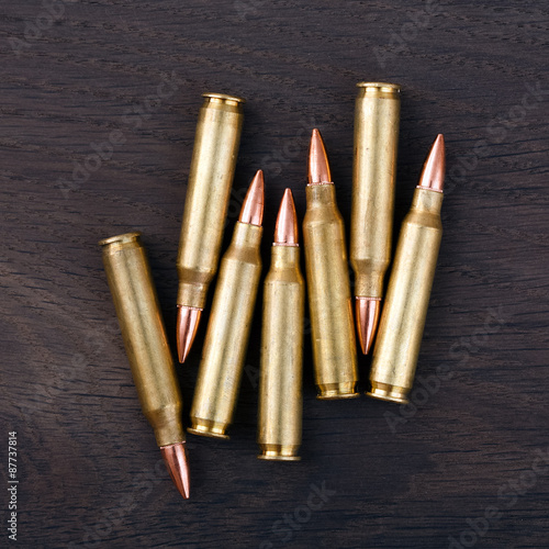 Several rifle cartridges on vintage wooden surface.