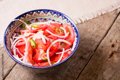 Pilaf and achichuk salad in handmade plate on wooden background photo