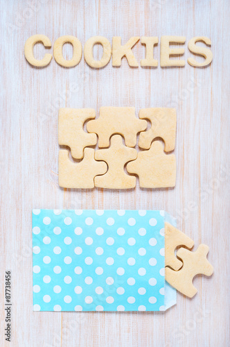 Cookies in the form of puzzles and letters on the wooden table