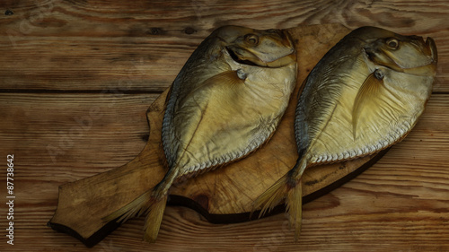 two smoked fish on a wooden cutting board closeup