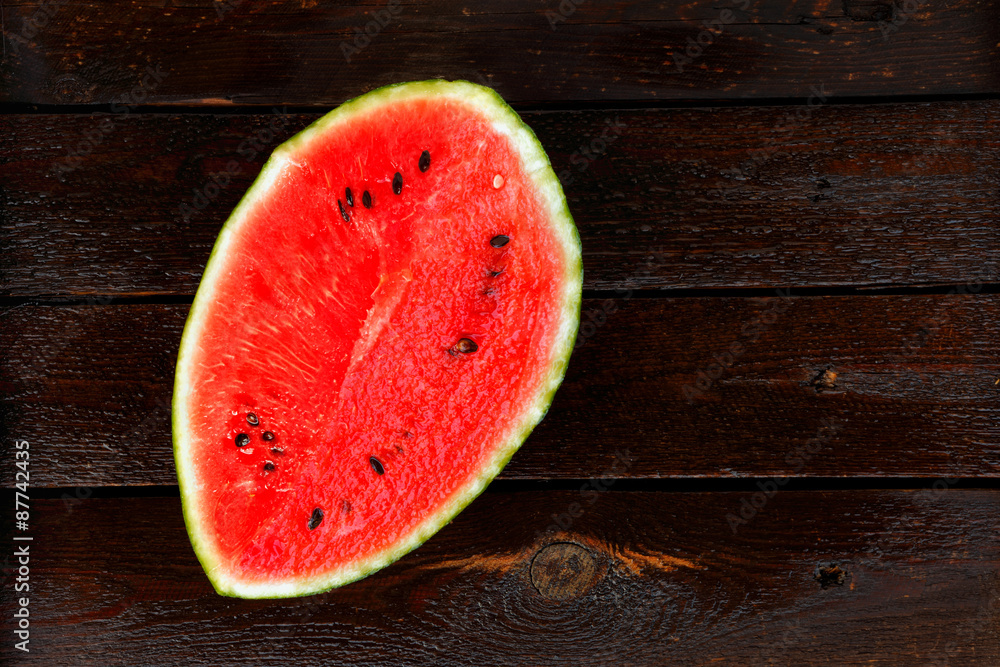Sliced watermelon on dark wet wooden table seen from above Sliced watermelon on dark wet wooden table seen from above