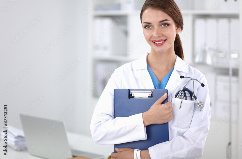 Smiling female doctor with a folder in uniform standing at Smiling female doctor with a folder in uniform standing at