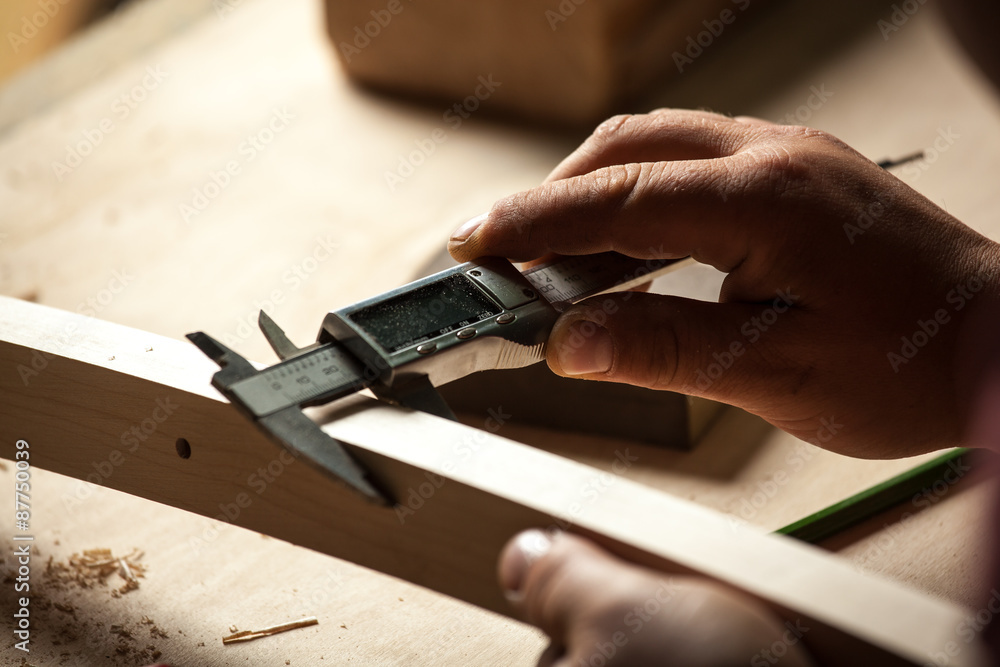 Carpenter measuring chair part with electric callipers. Carpenter measuring chair part with electric callipers.