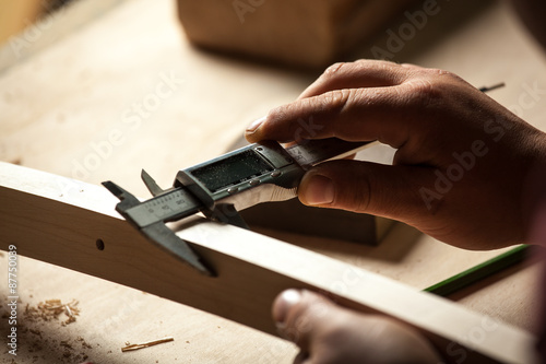 Carpenter measuring chair part with electric callipers.