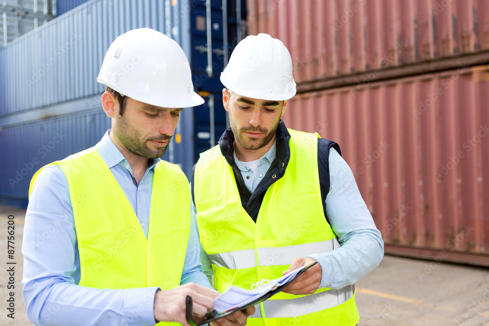 Fototapeta premium Dock worker and supervisor checking containers data on tablet