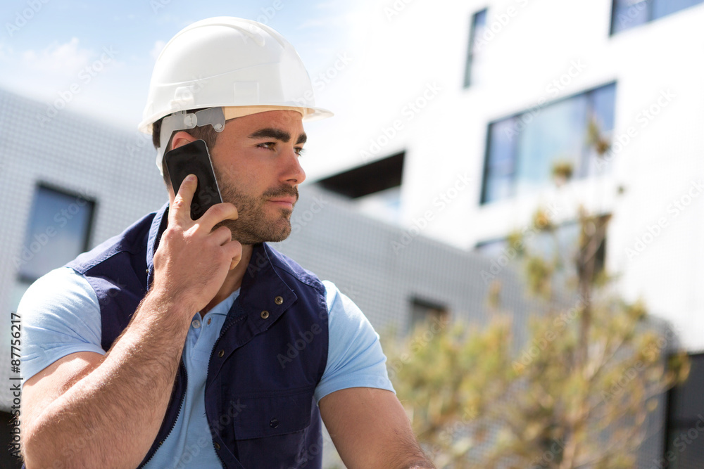 Yong attractive worker using mobile phone on a construction sit Yong attractive worker using mobile phone on a construction sit