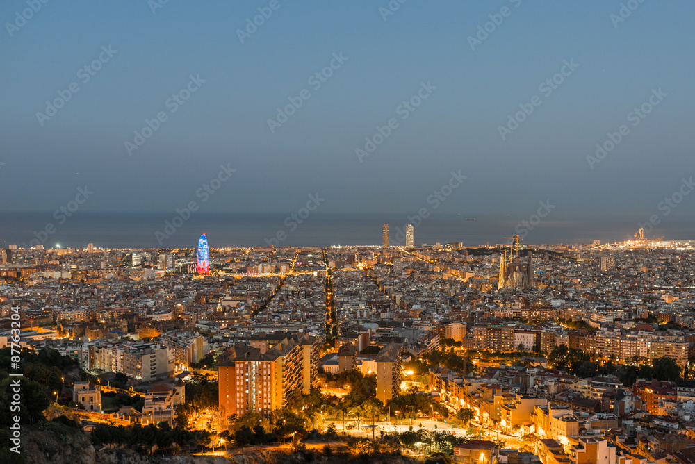 Top view and night photography from an illuminated Barcelona. The panorama shows the famous Sagrada Familia, the illuminated Torre Agbar and the Towers of the Port Olimpic until the harbor