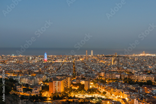 Top view and night photography from an illuminated Barcelona. The panorama shows the famous Sagrada Familia, the illuminated Torre Agbar and the Towers of the Port Olimpic until the harbor