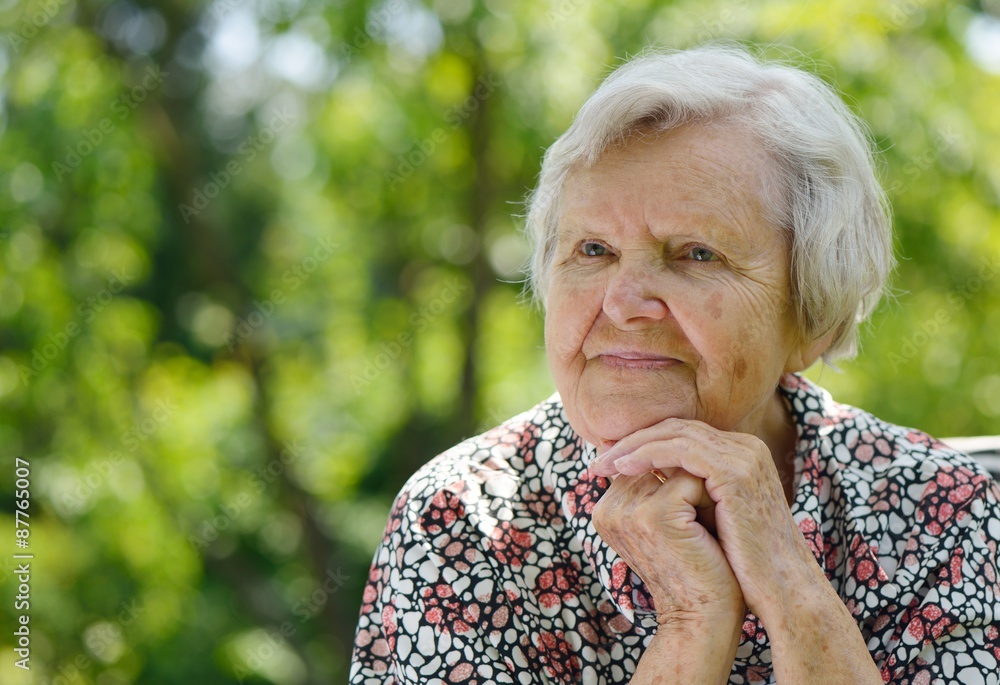 Senior woman smiling and dreaming in garden.