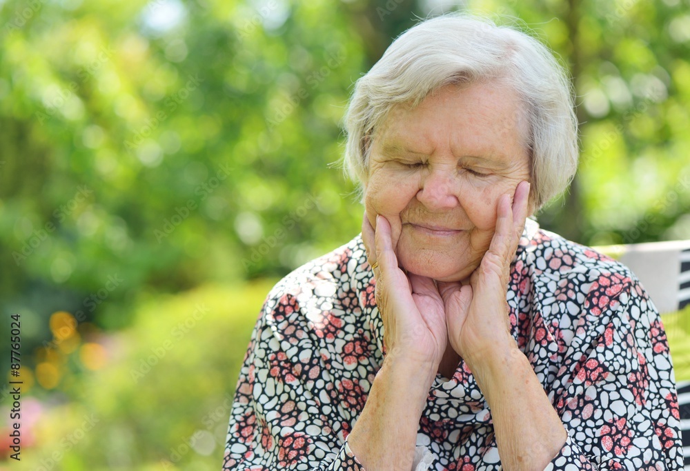 Senior woman smiling and dreaming in garden.