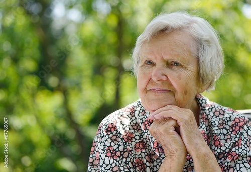 Senior woman smiling and dreaming in garden.