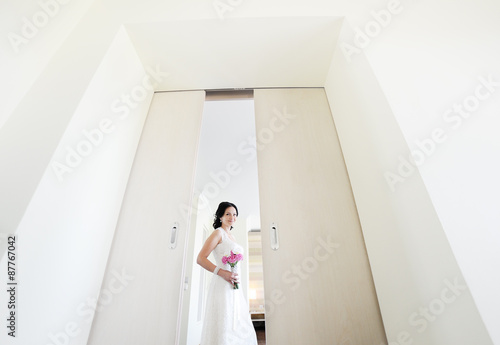 beautiful bride with a wedding bouquet stands in the doorway