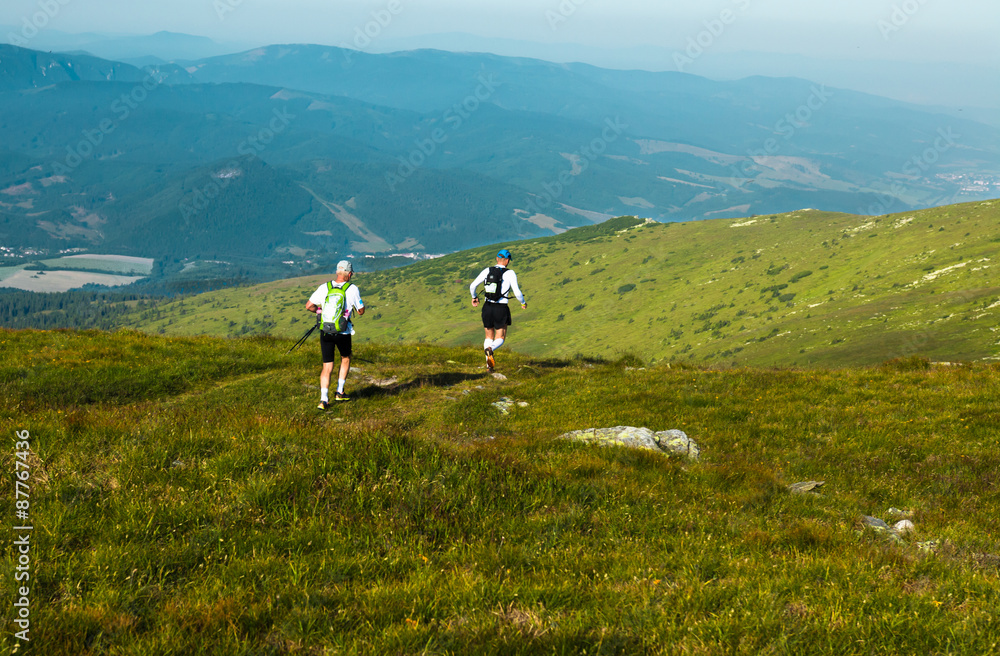 Two vigorous senior runners training on the trail in the mountains