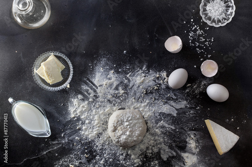 Dough on black table with flour and ingredients photo