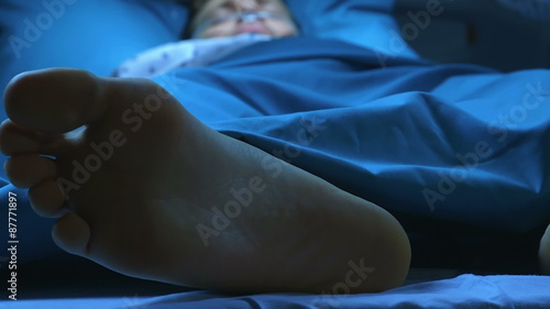 Doctor giving electric shocks with defibrillator to dying man who lies in a hospital bed to try to revive him.
Cold atmosphere.