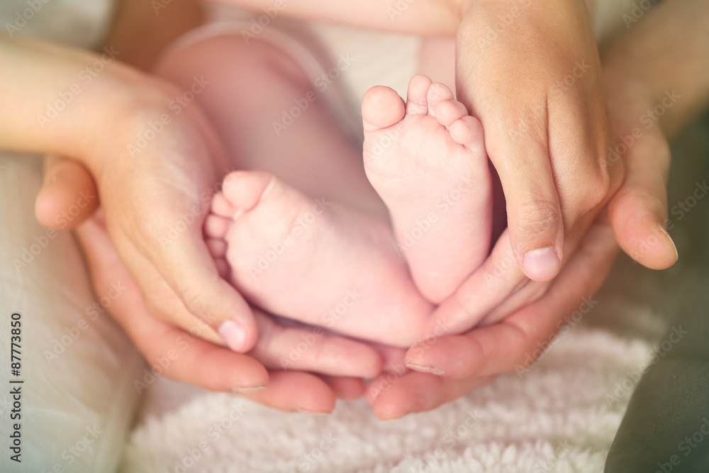 Adult hands holding baby feet, closeup Adult hands holding baby feet, closeup