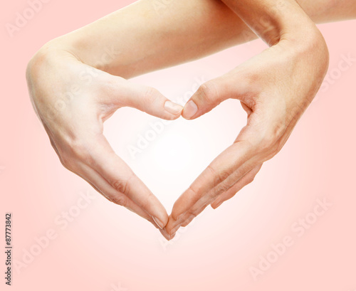 Hands in shape of heart on light background