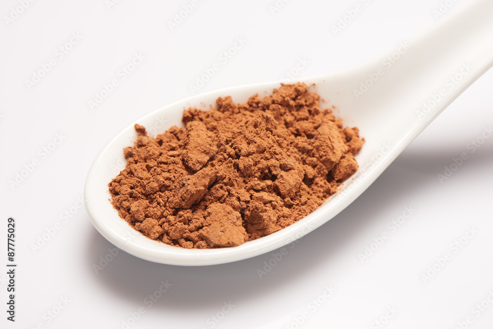 Pile of cacao powder in white ceramic spoon Pile of cacao powder in white ceramic spoon
